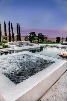 an outdoor hot tub surrounded by trees at dusk