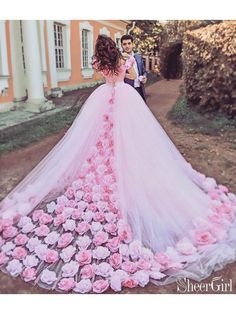 a woman in a wedding dress with pink flowers on the ground next to a man wearing a tuxedo