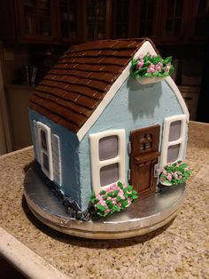 a cake shaped like a house with flowers on the outside and brown trim around the roof