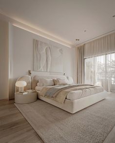 a large white bed sitting in the middle of a bedroom next to a tall window