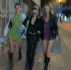 three women are walking down the sidewalk at night