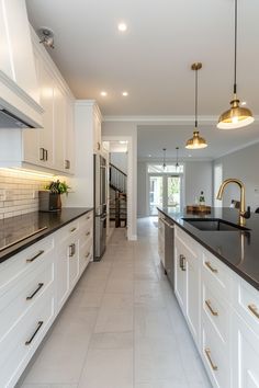 a large kitchen with white cabinets and black counter tops, along with an island in the middle