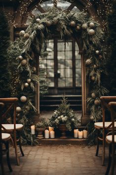 a christmas wreath with candles in front of an arched window surrounded by greenery and lights