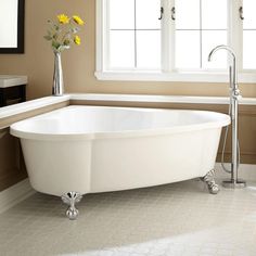 a white bath tub sitting in a bathroom next to a window with flowers on it