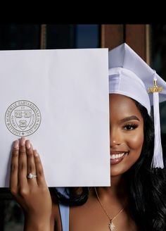 a woman wearing a graduation cap and gown holding up a piece of paper