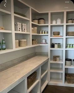 an empty walk in closet with white shelving and baskets on the shelves, along with other items