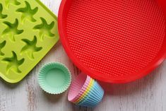 a red tray with cupcake liners next to other baking supplies on a white wooden surface