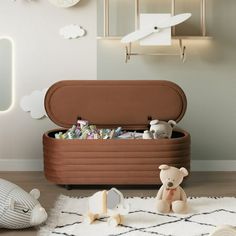 a teddy bear sitting on top of a rug next to an open trunk filled with toys