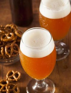 two glasses of beer with pretzels in the background