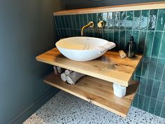 a white bowl sink sitting on top of a wooden counter next to a green tiled wall