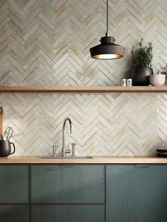 a kitchen with green cabinets and white tile backsplash, wood counter tops and hanging lights