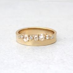 a gold ring with three stones on the side and two rows of diamonds in each band