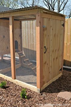 a chicken coop in the middle of a yard with a fence around it and a chair inside