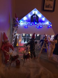 several elf figurines in front of a house decorated with christmas lights