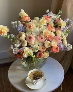 a vase filled with flowers sitting on top of a table next to a tea cup