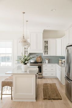 a kitchen with white cabinets and an island in the middle, along with a rug on the floor