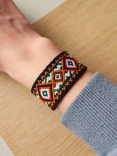 a woman's hand wearing a bracelet with colorful beaded designs on the wrist