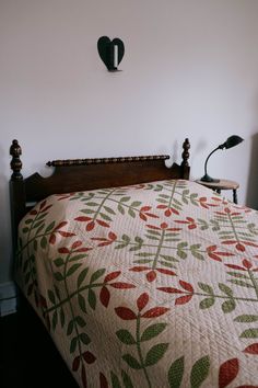 a bed with a quilt on top of it and a clock above the headboard