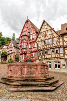 a fountain in front of some buildings on a cobblestone street