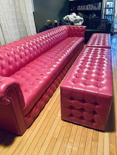 two red leather couches sitting on top of a wooden floor