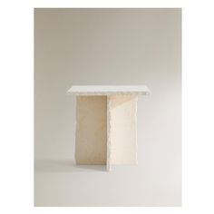 a small white table sitting on top of a white floor next to a gray wall