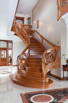 a large wooden staircase in the middle of a living room with marble floors and walls