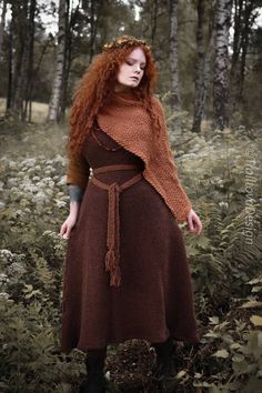 a woman with red hair wearing a brown dress and scarf in the middle of a forest