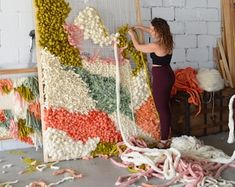 a woman is working on an art project with yarn and cottons in the background