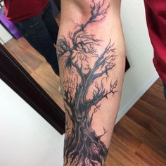 a man's leg with a tree tattoo on the side of his arm,