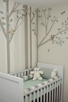 a baby's room with a white crib and tree mural on the wall