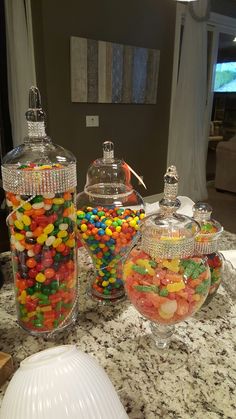 three glass jars filled with candy on top of a counter