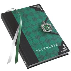 a harry potter notebook with a sly crest on it and a ribbon tied around the book