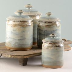 three canisters sitting on top of a wooden table next to each other with lids