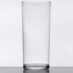 a tall glass sitting on top of a table next to a white wall in the background