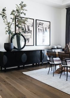 a dining room table with chairs and a vase on top of it in front of two framed pictures