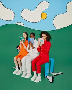 three women are sitting on a bench and one woman is holding up two small books