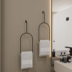 two towels are hanging on the wall near a sink and mirror in a modern bathroom