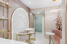 the inside of a salon with white counter tops and gold accents on the walls, along with pink velvet chairs