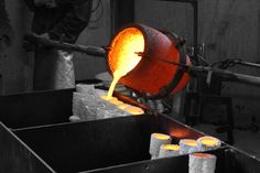 a person pouring liquid into a metal container with candles in front of it on a machine