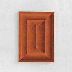 an orange square shaped object mounted on the wall with a white stucco wall behind it