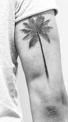 a black and white photo of a palm tree on the back of a man's arm