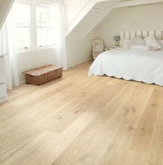 an attic bedroom with white walls and wood flooring on the ceiling, along with a bed