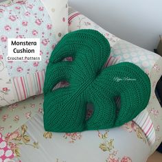 two green crocheted pillows sitting on top of a bed next to each other