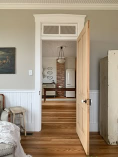 an open door leading to a kitchen and living room with white walls, wood flooring and wooden floors