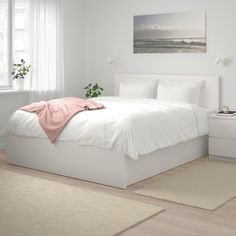 a bedroom with white walls and flooring has a bed, nightstands, and window