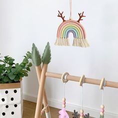 several wooden toys are hanging on a rack in front of a wall with a potted plant