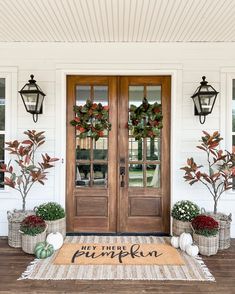 the front door is decorated with wreaths and potted plants