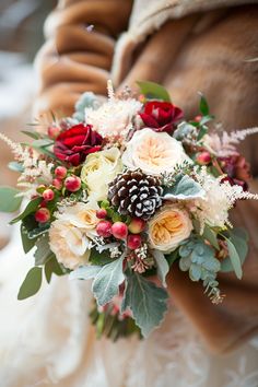 a bridal holding a bouquet of flowers and pine cones