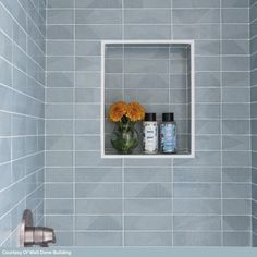 a vase with flowers in it sitting on a shelf next to a shower faucet