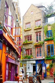 an alleyway with colorful buildings and people sitting at tables